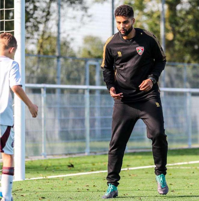 Jock de Burgo coacht een jeugdspeler op het trainingsveld